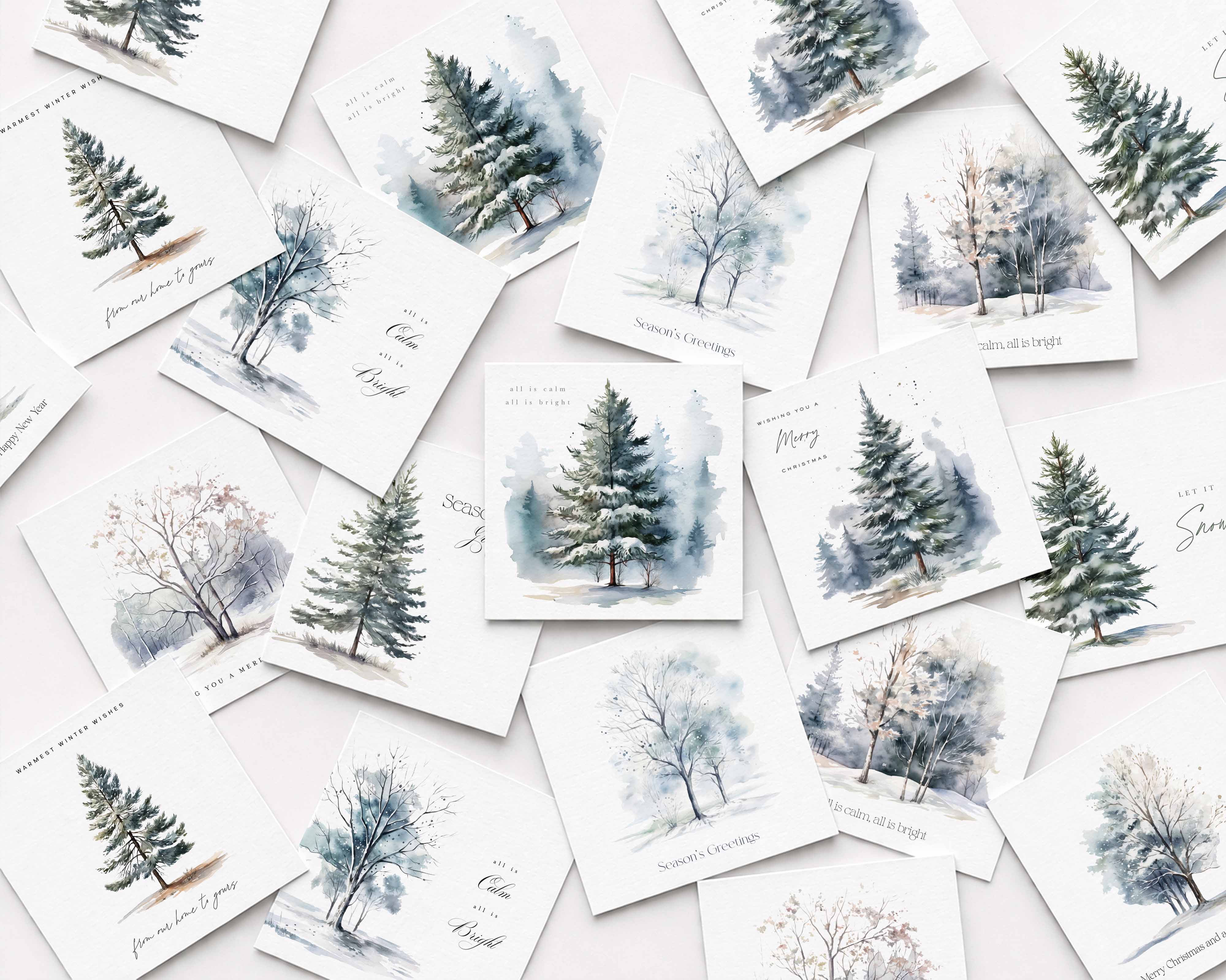 A flat-lay arrangement of multiple Christmas cards featuring watercolor winter trees and snowy forest scenes in soft blue, gray, and green tones on white backgrounds.