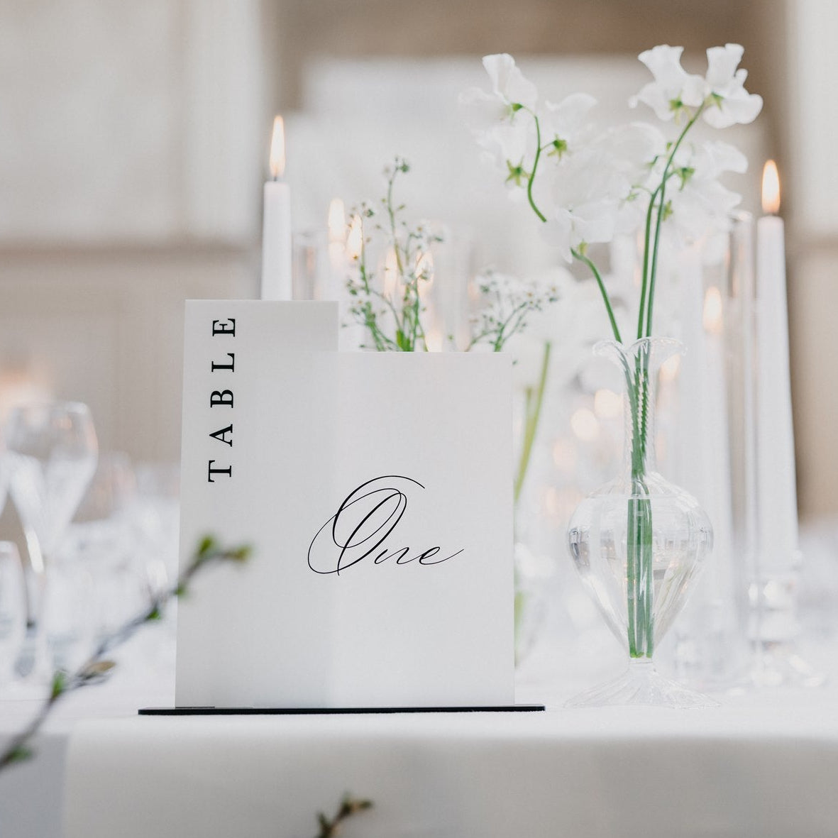 Table setting with a 'TABLE One' sign and floral arrangement at a weddingbreakfast