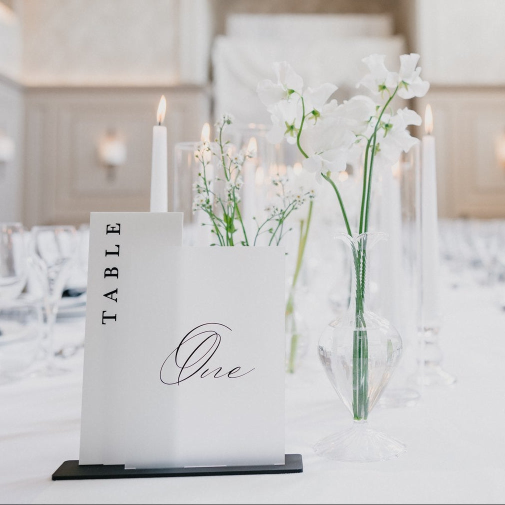Elegant dining room setup with floral centerpieces and table numbers.