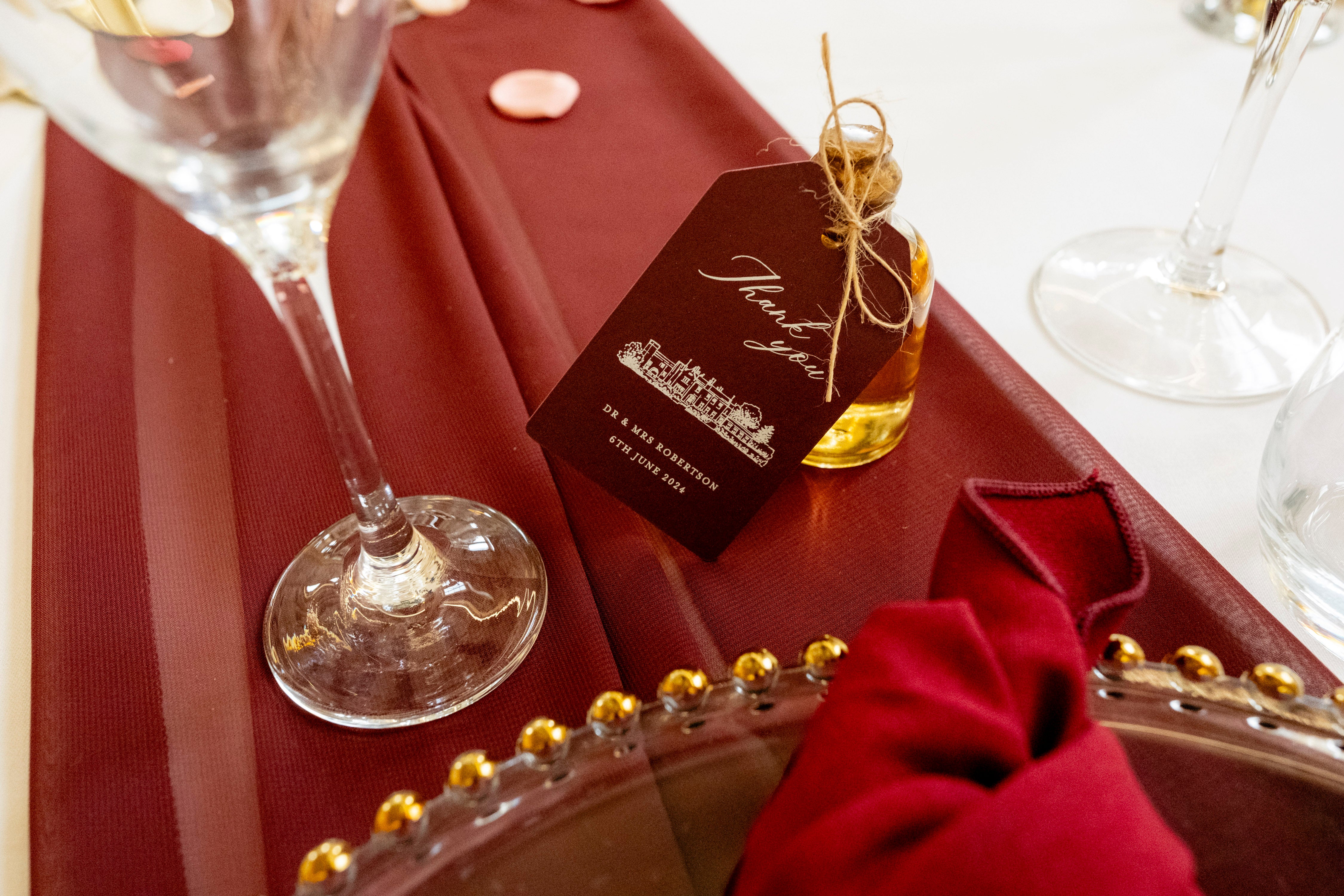 Table setting with a wine glass, red napkin, and bottle of wine on a red tablecloth.