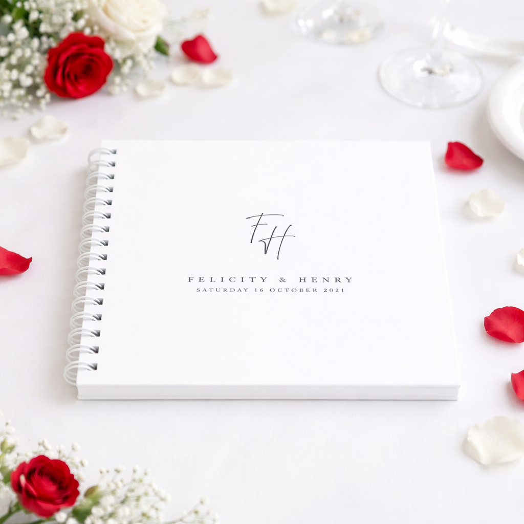 white guest book on table cloth with red and white petals and flowers