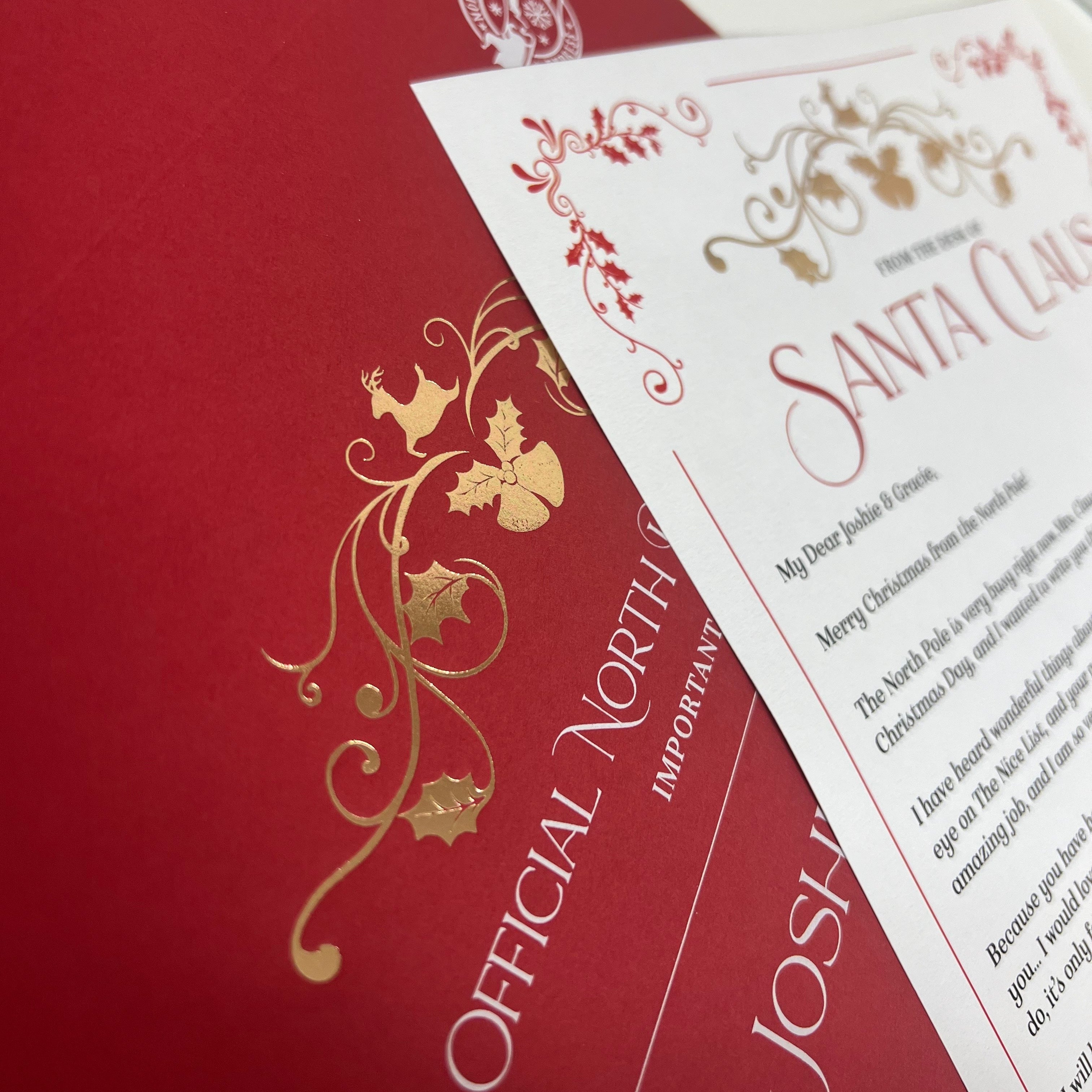 A close-up of a red envelope and letter from santa with gold foil floral scrollwork and the words 'OFFICIAL NORTH.