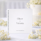White guestbook with 'Oliver & Victoria' text on a light background with flowers