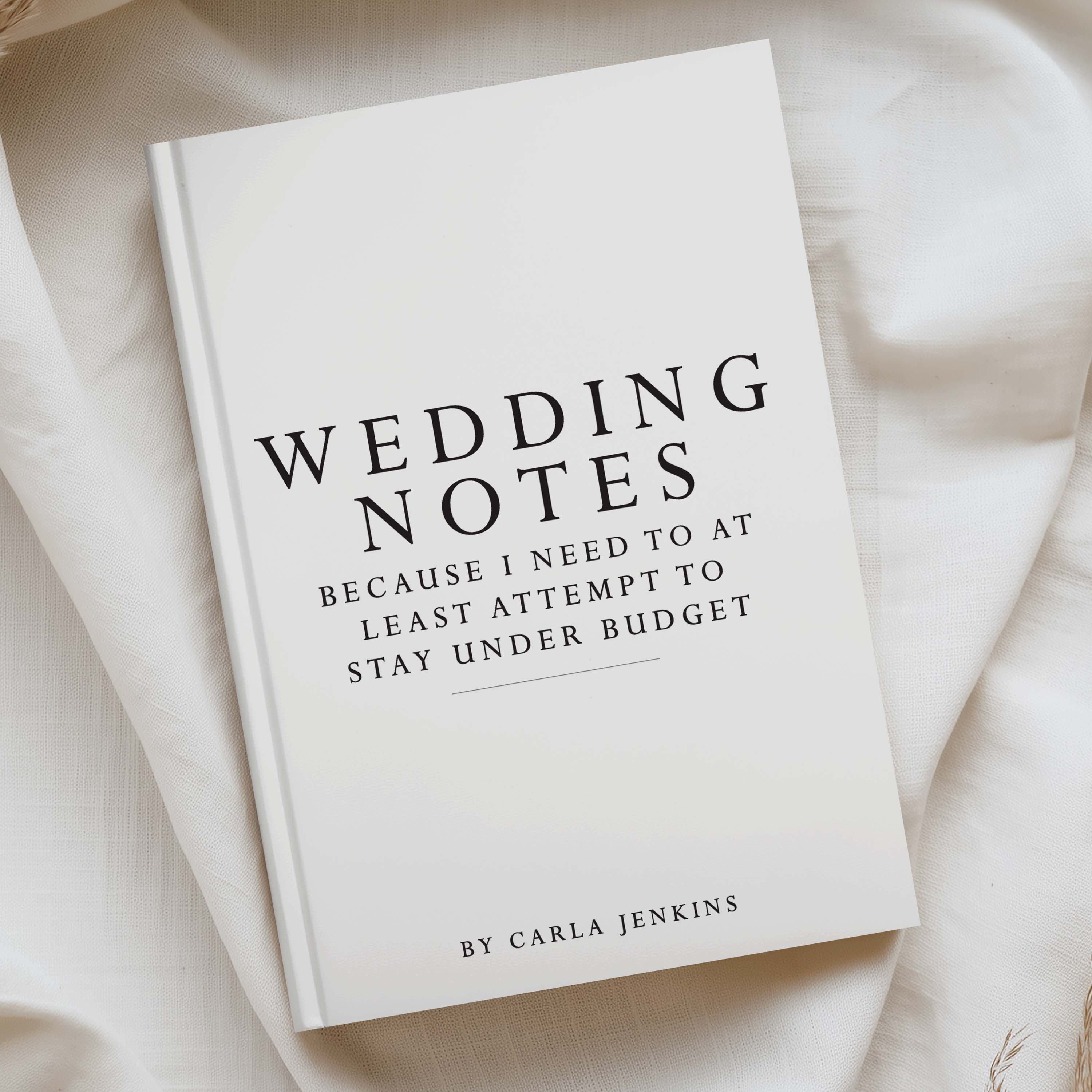 A hardcover notebook titled 'WEDDING NOTES' by Carla Jenkins, styled on a draped cream fabric background.