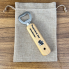 Wooden bottle opener with 'Professional beer connoisseur' text on a fabric pouch.